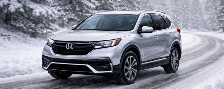 Honda SUV driving in snowy winter conditions, showcasing advanced safety features.