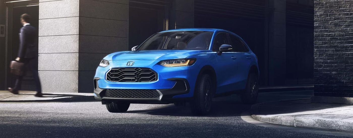 A blue 2027 Honda HR-V Sport shown driving out of an alley.